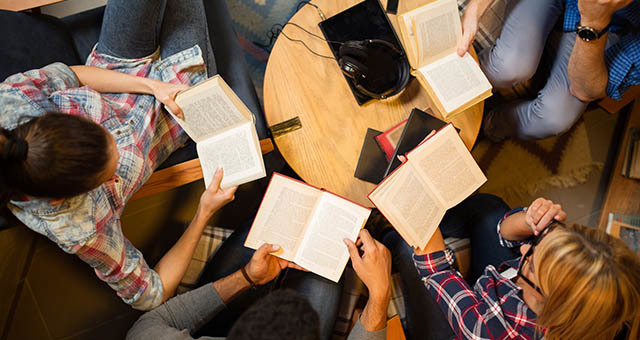 People discussion books sitting around a table.