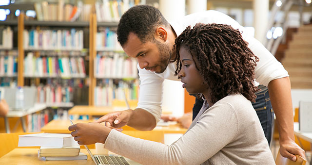 People working on a laptop in a library.